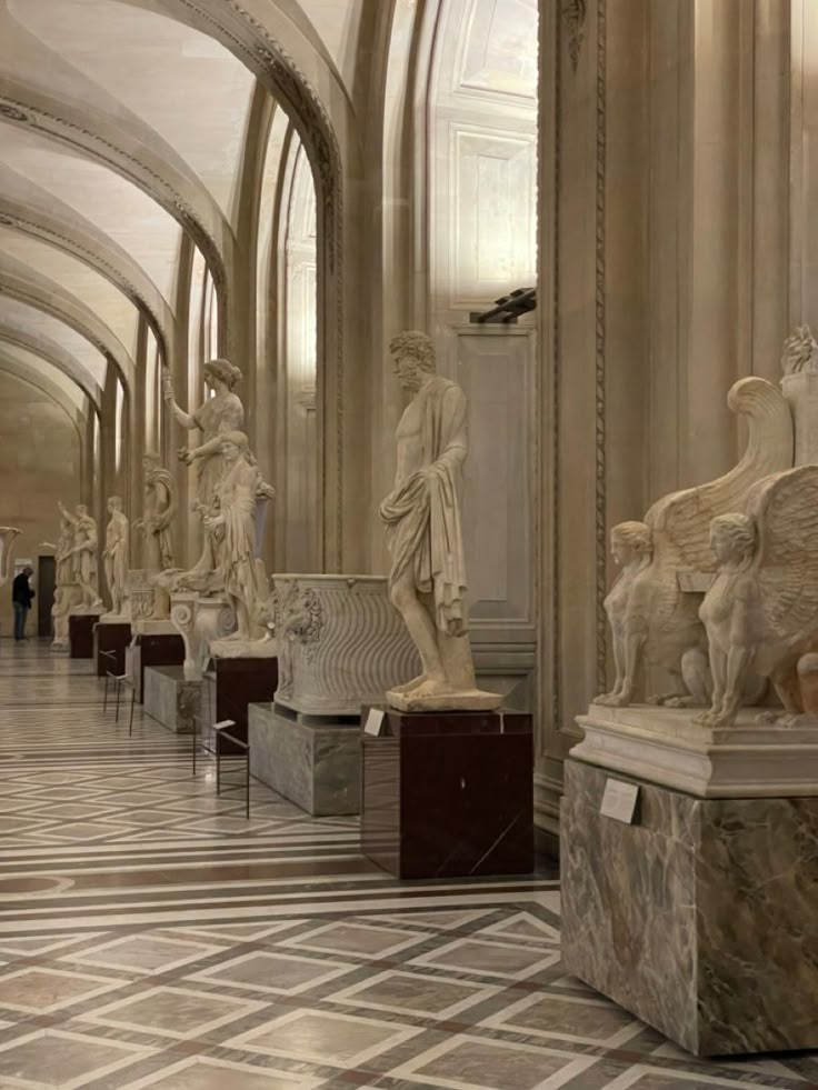 many statues are lined up in the middle of a room with marble floors and walls