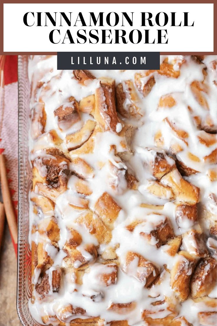 cinnamon roll casserole with icing on top in a glass baking dish, next to cinnamon sticks