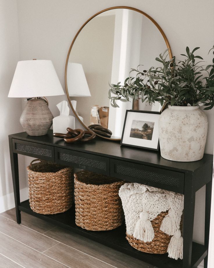 a black table with three baskets and a mirror on top of it next to a lamp