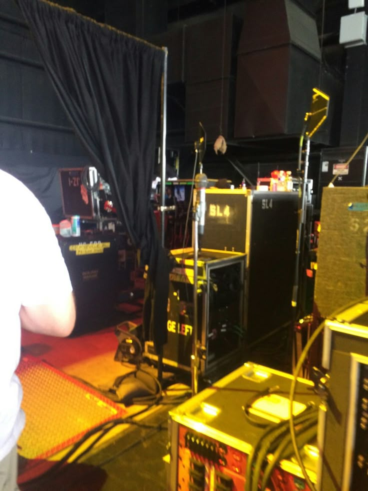 a man standing in front of some speakers and other electronic equipment on a yellow floor