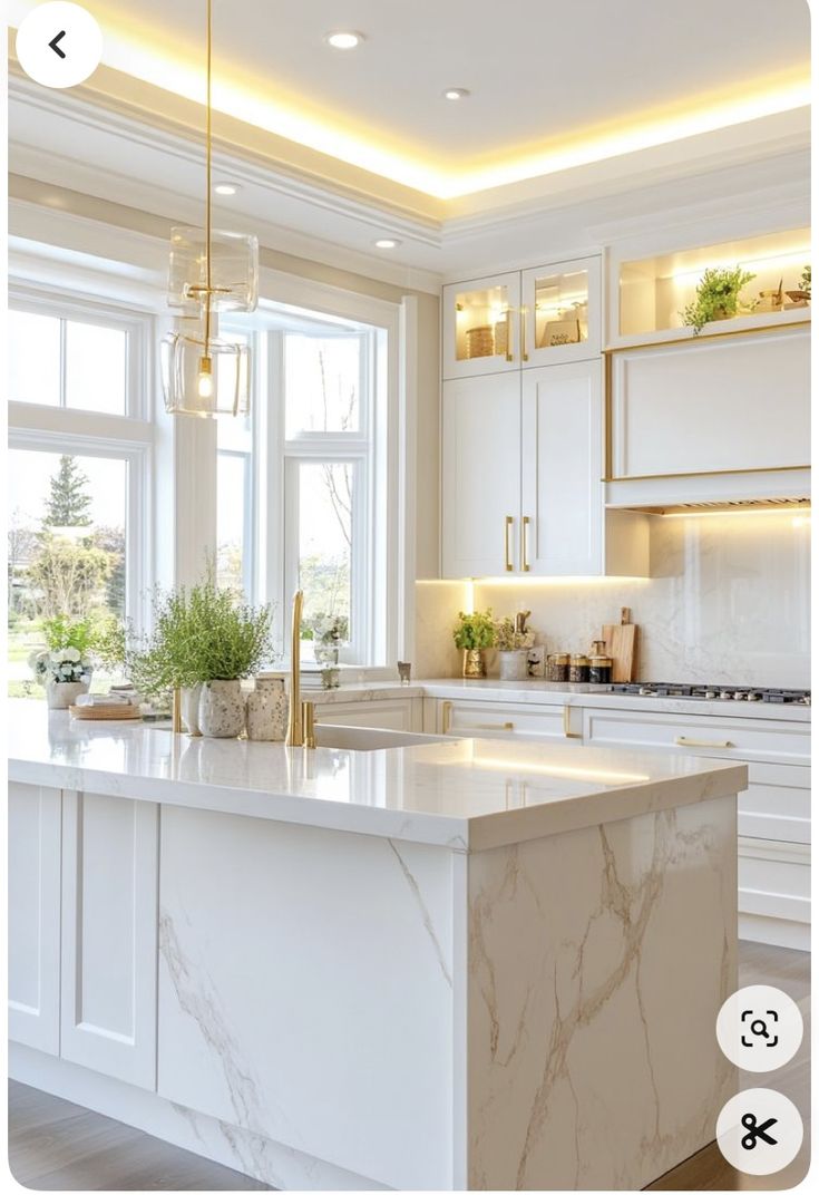 a kitchen with white cabinets and marble counter tops, along with an island in the middle