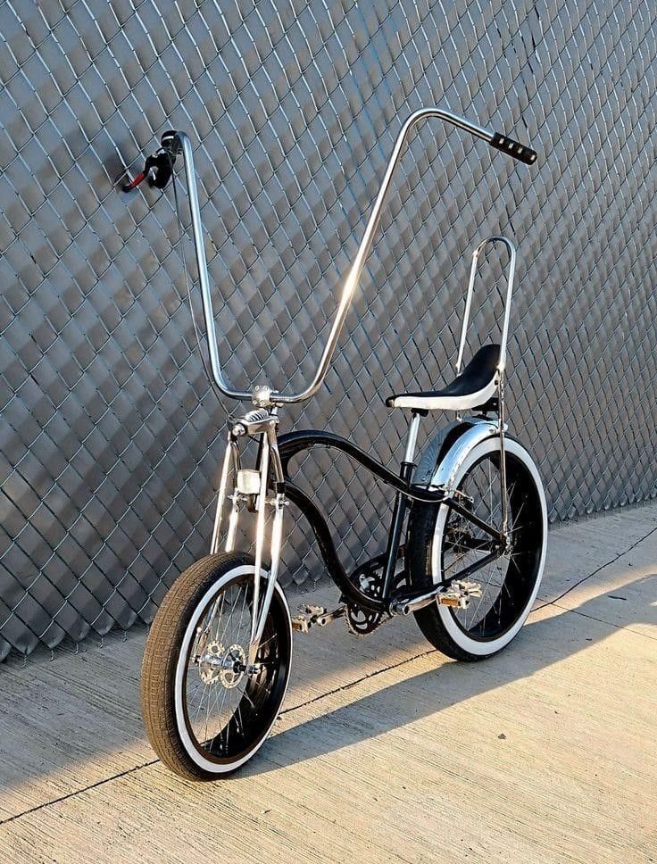 a black and white bike parked next to a wall with a metal handlebar on it