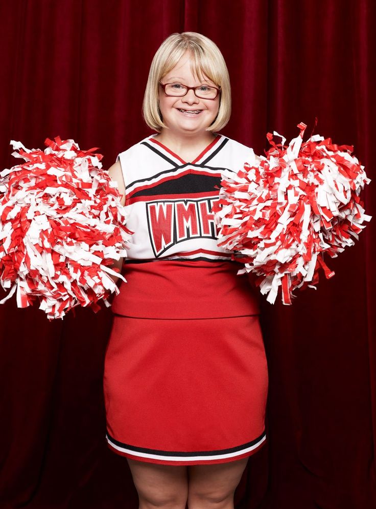 a woman in red and white cheerleader uniform posing for a photo with her pom poms