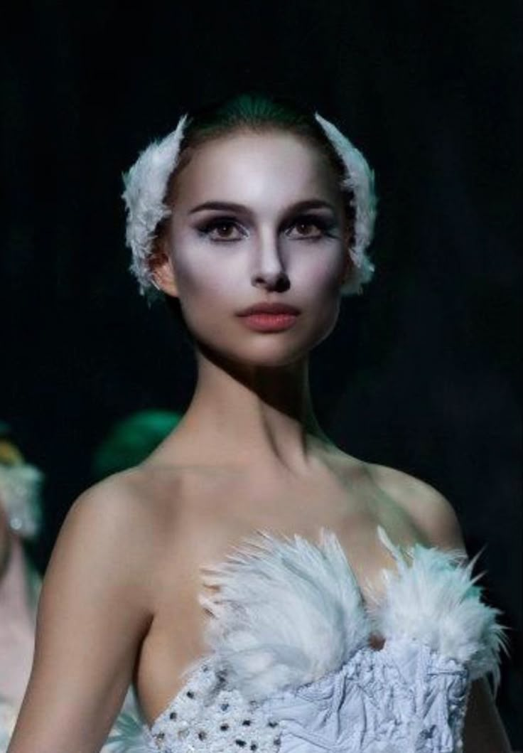 a woman in a white dress with feathers on her head