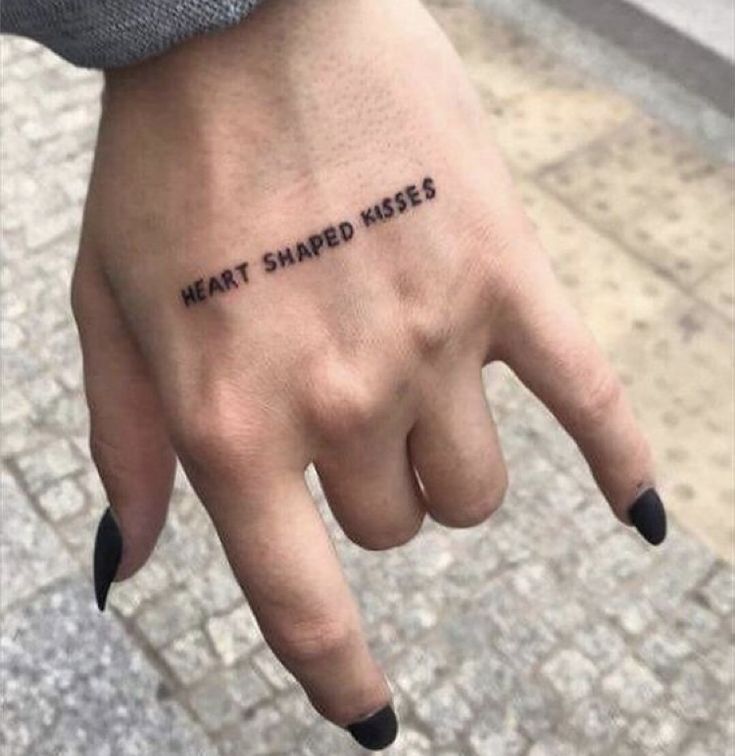 a person's hand with the words heart shaped kisses tattooed on it