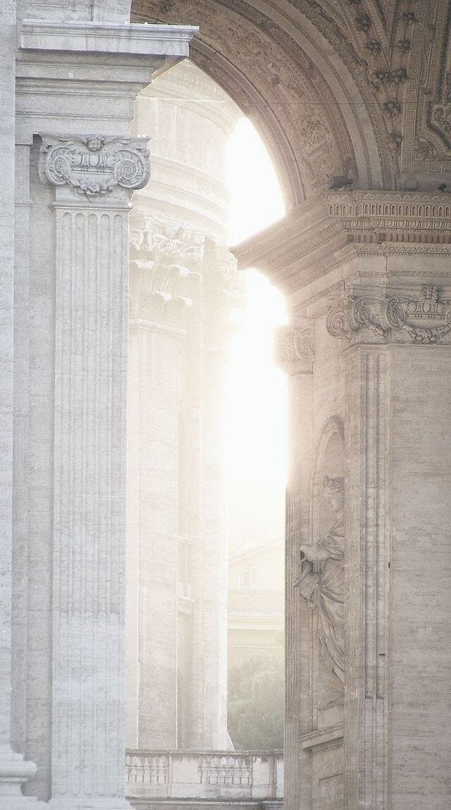 the sun is shining through an arch in a stone building with statues on either side