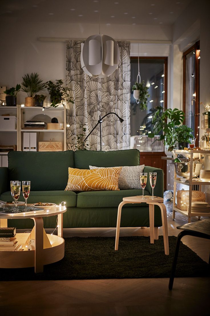 a living room filled with furniture next to a tall window covered in plants and greenery