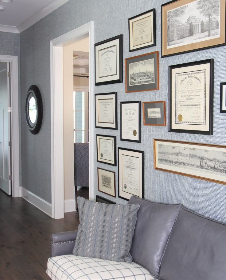 a living room filled with furniture and framed pictures on the wall above it's doorway