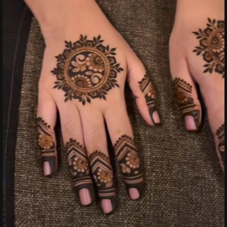 two hands with henna tattoos on them, one is showing off the intricate design