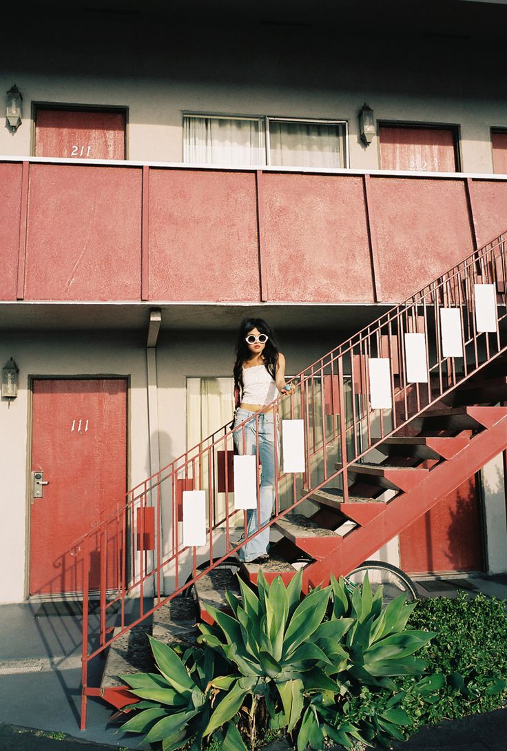 a woman standing on top of a set of stairs next to a building with red doors