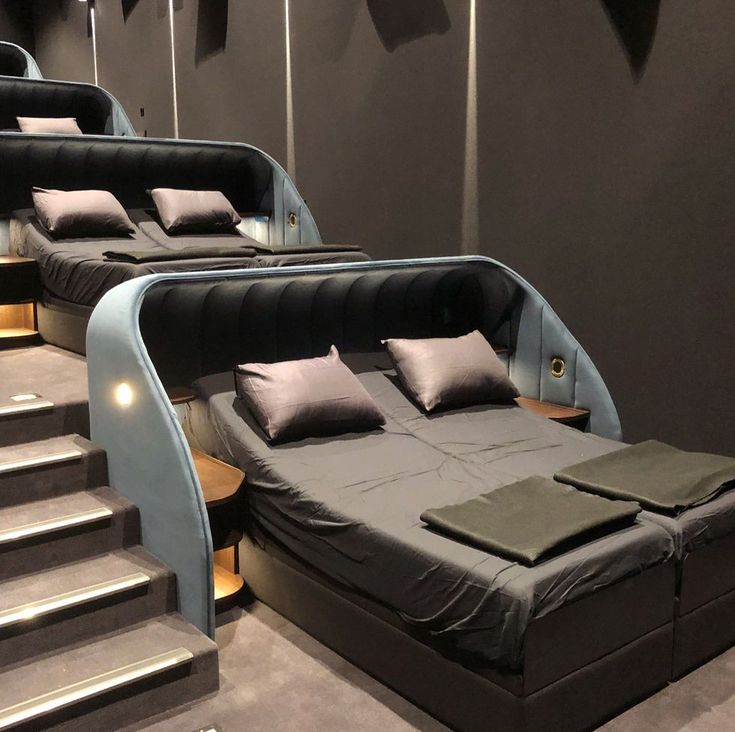 there are three beds in the room with black sheets and pillows on them, along with some stairs