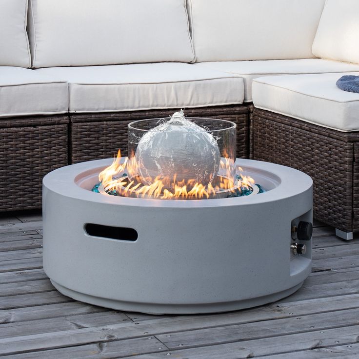 a fire pit sitting on top of a wooden floor next to a couch and table