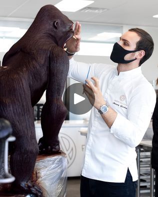 a man wearing a black face mask while standing next to a statue of a bear