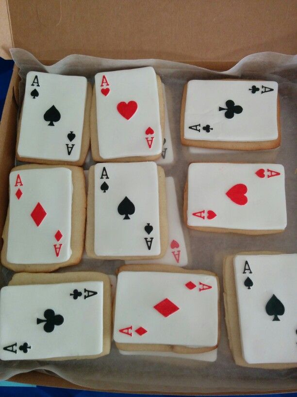 cookies decorated with playing cards and spades are in a cardboard box on the table