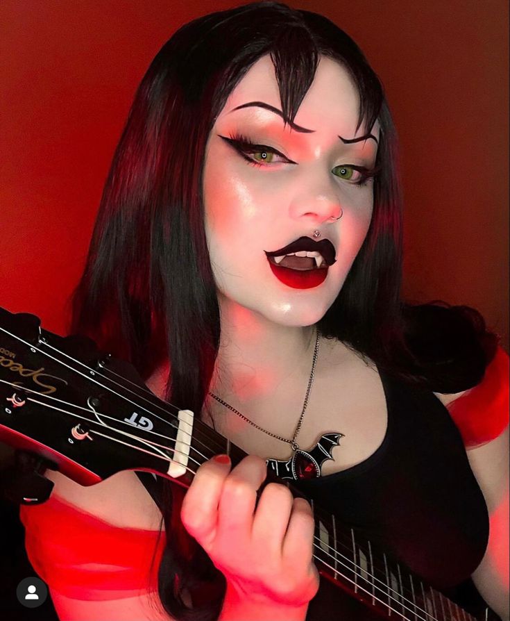 a woman with black hair and makeup holding a guitar in her right hand while wearing red lipstick