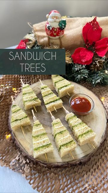 sandwiches are arranged on a wooden plate with dipping sauce and christmas decorations in the background