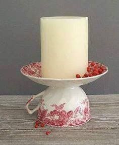 a white candle sitting on top of a red and white bowl filled with raspberries