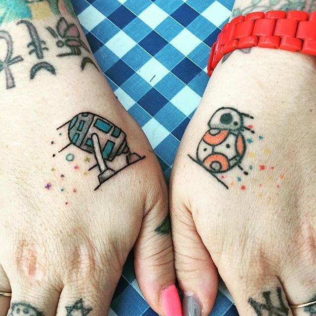 two people with matching tattoos on their hands, one has an elephant and the other has a dog