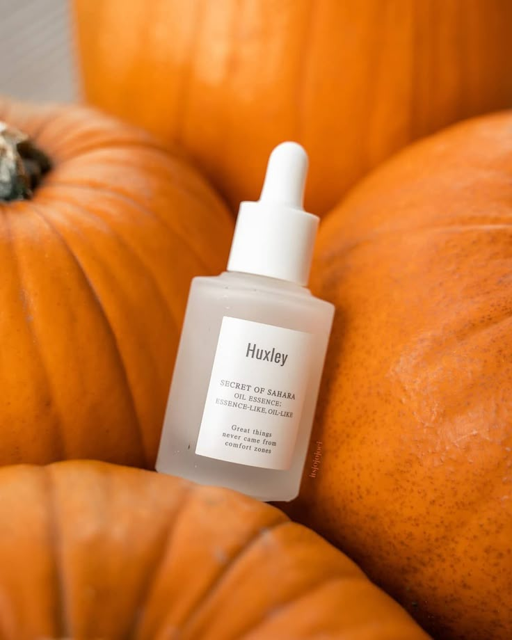 a bottle of liquid sitting on top of pumpkins