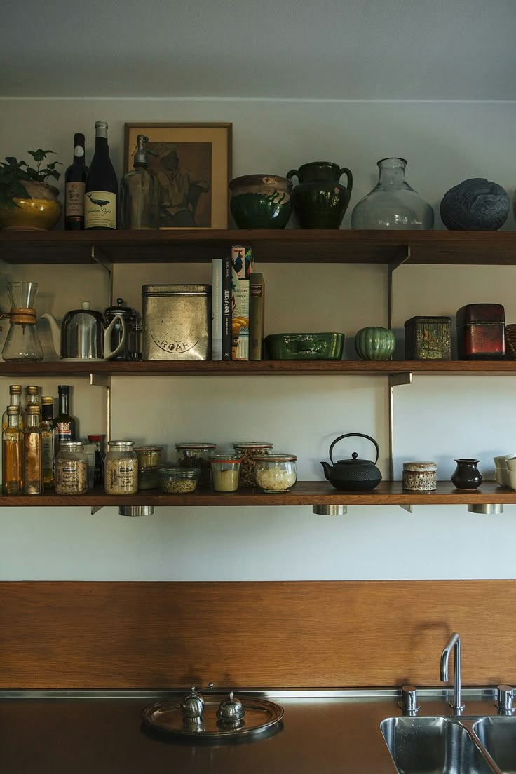 the shelves above the sink are filled with kitchen items