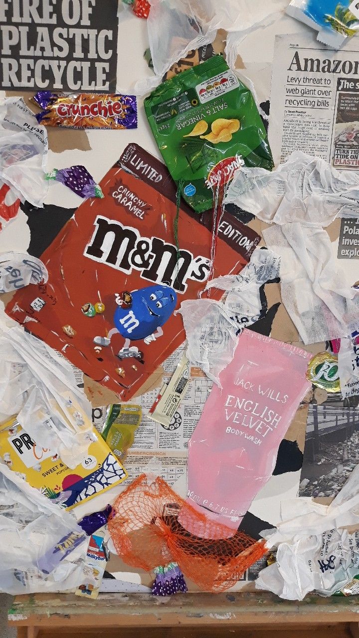 a pile of garbage sitting on top of a wooden table next to a wall covered in paper