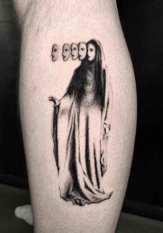 a man's leg with an image of the virgin mary and three heads on it