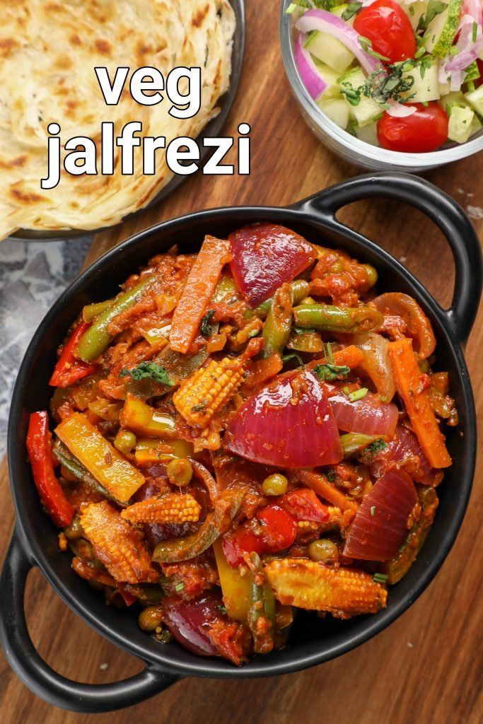 a pan filled with food next to a bowl of salad and pita bread on a wooden table