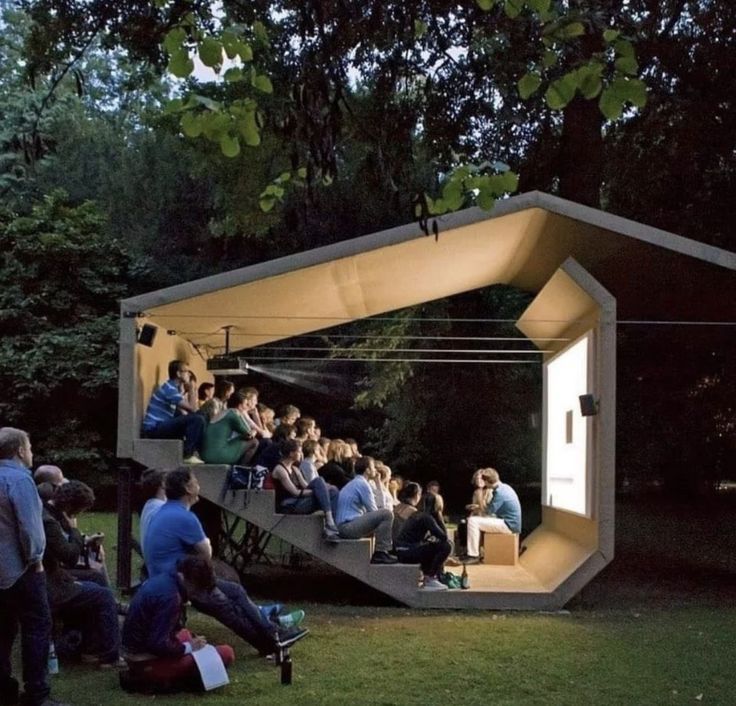 people are sitting on the steps in an open air area with trees and grass behind them