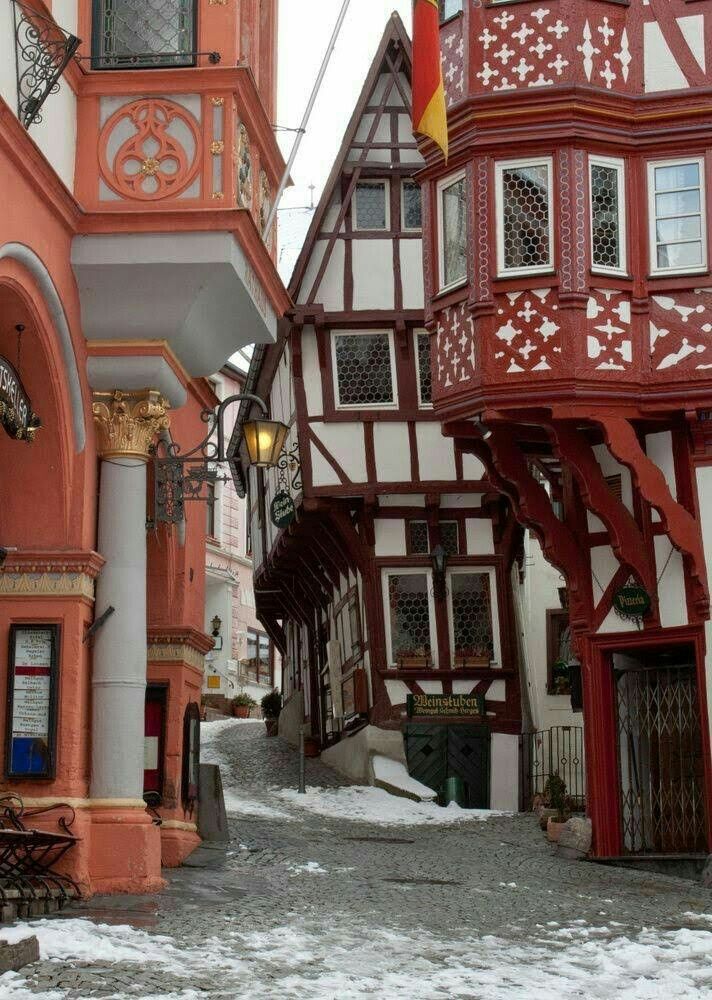 an old european street with red and white buildings on both sides, snow covered ground in the foreground