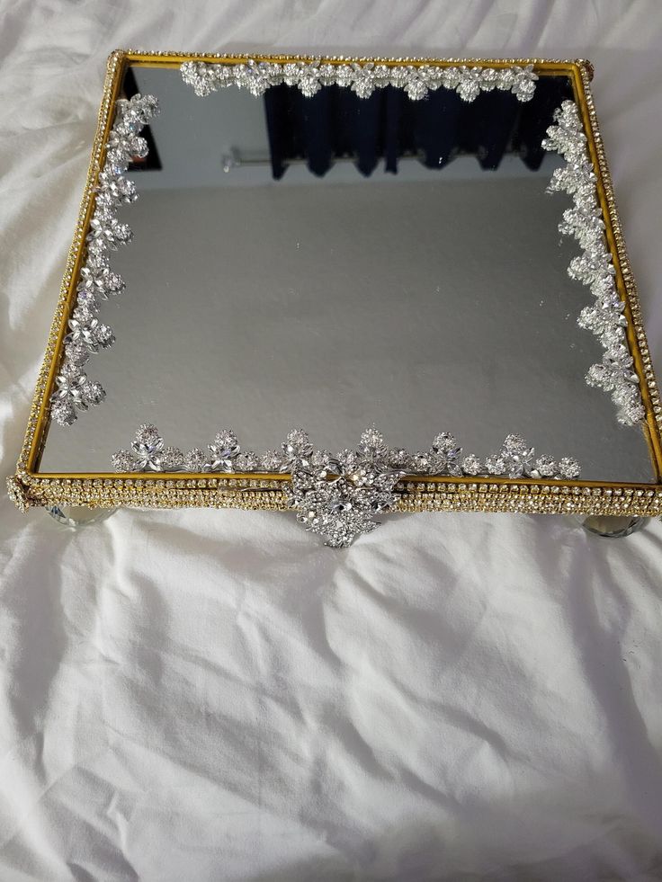 a mirror that is sitting on top of a white sheet with gold trimmings