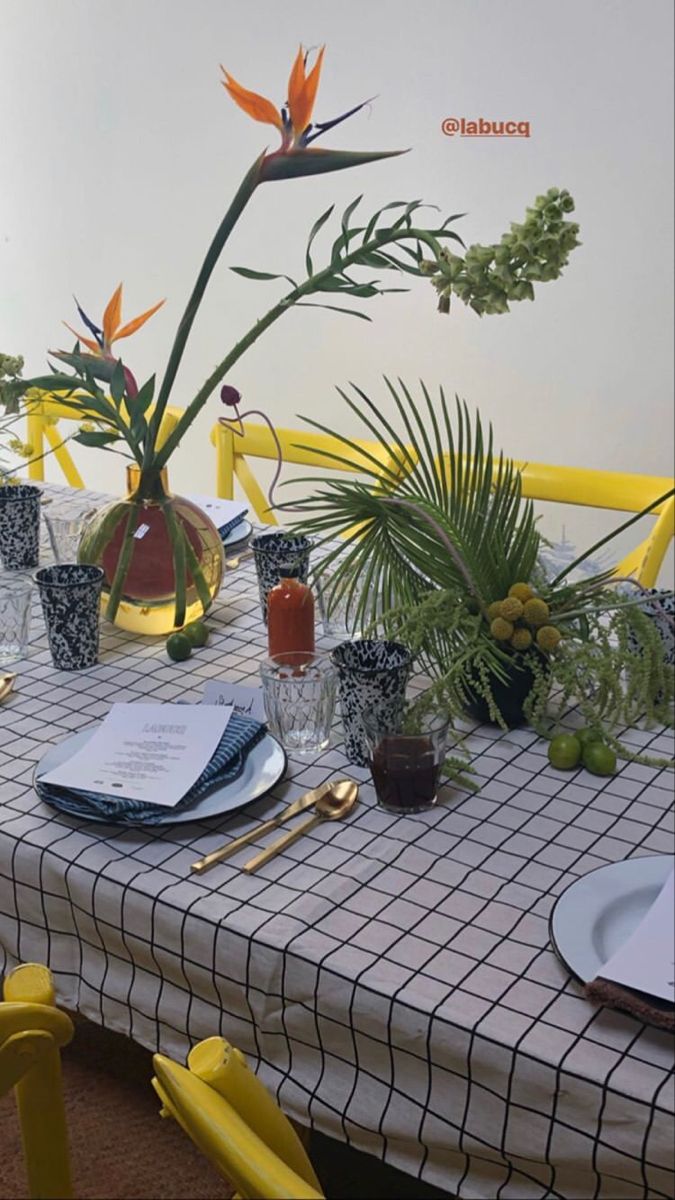 the table is set with yellow chairs and place settings