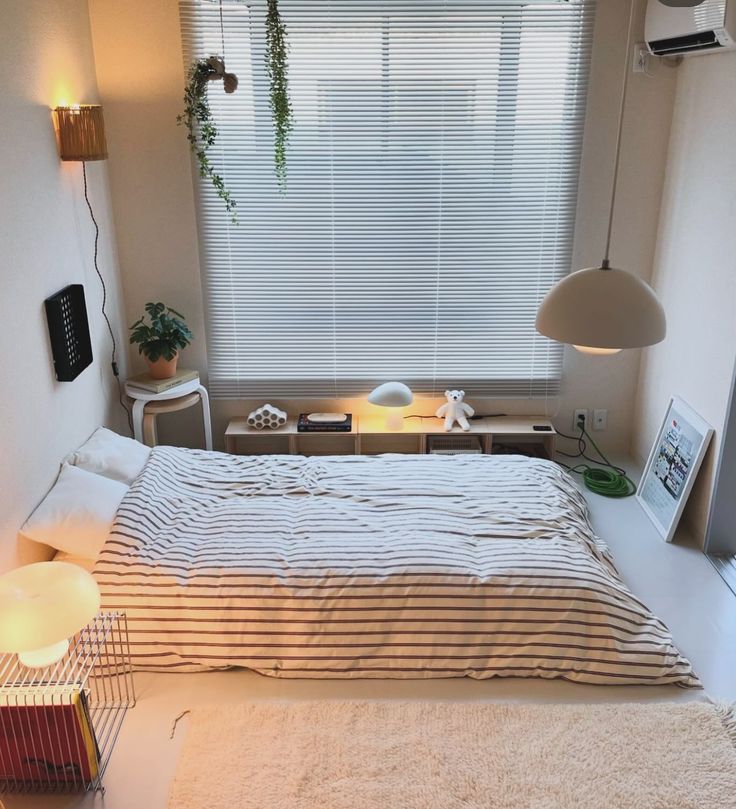 a bedroom with a bed, nightstands and plants in the window sill above it