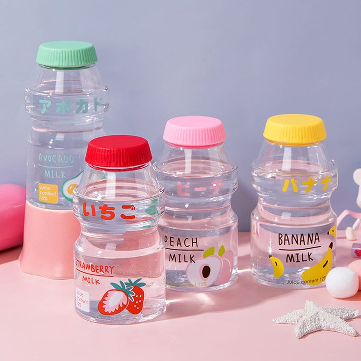 three plastic water bottles sitting next to each other on a pink surface with various items around them