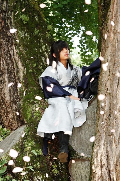 a woman sitting on top of a tree next to a forest filled with lots of leaves