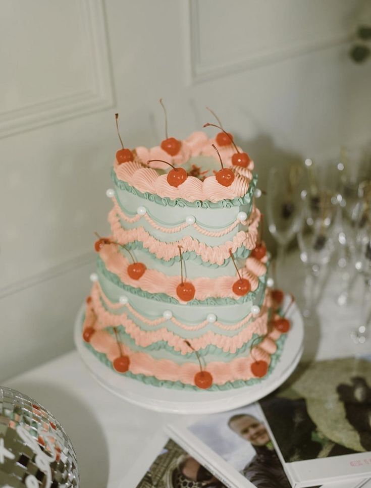 a three tiered cake sitting on top of a table next to pictures and wine glasses