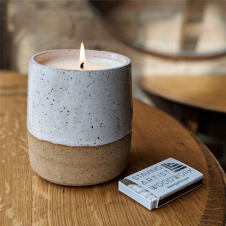 a white candle sitting on top of a wooden table next to a small box of matches