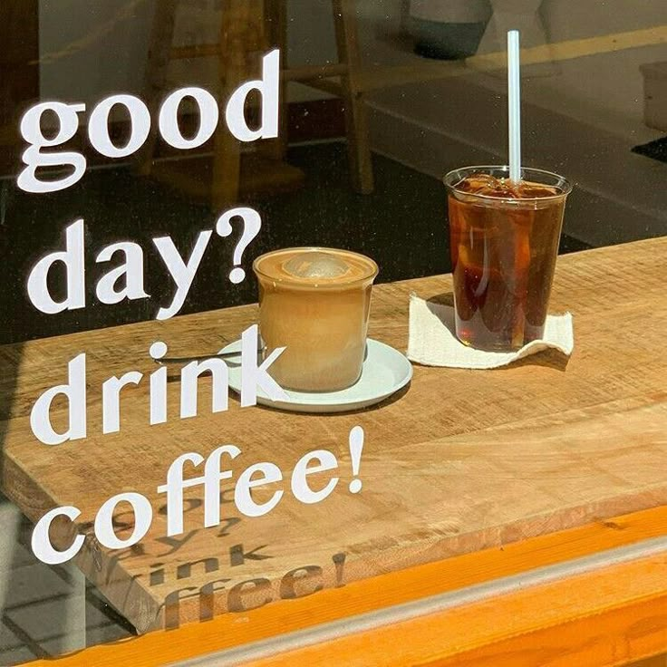 a cup of coffee sitting on top of a wooden table in front of a window