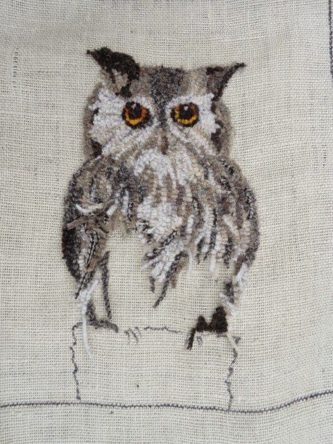 an embroidered owl is sitting on the edge of a piece of cloth