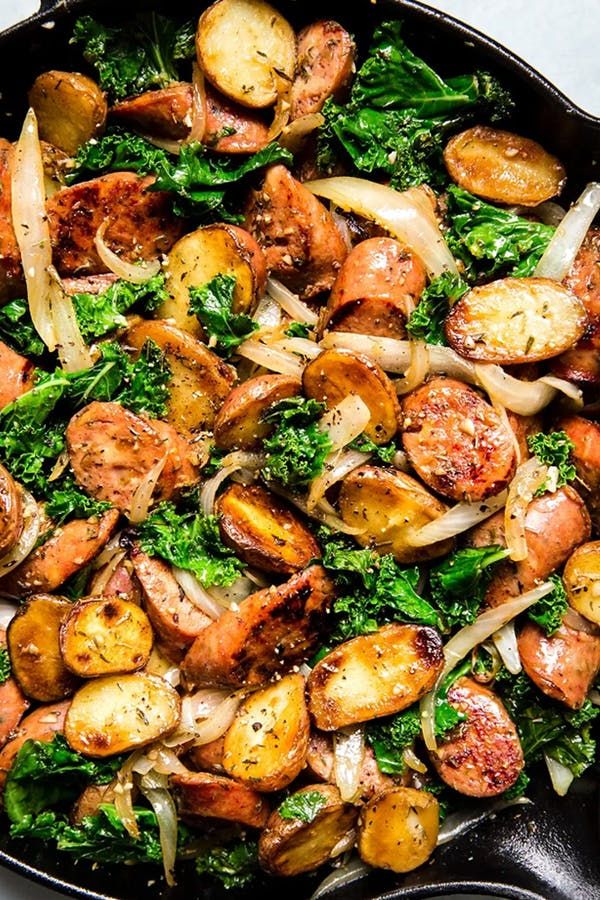 a skillet filled with sausage, onions and kale on top of a table