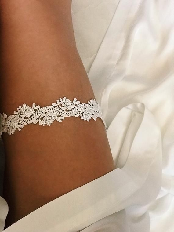 a woman wearing a white wedding garter on her arm