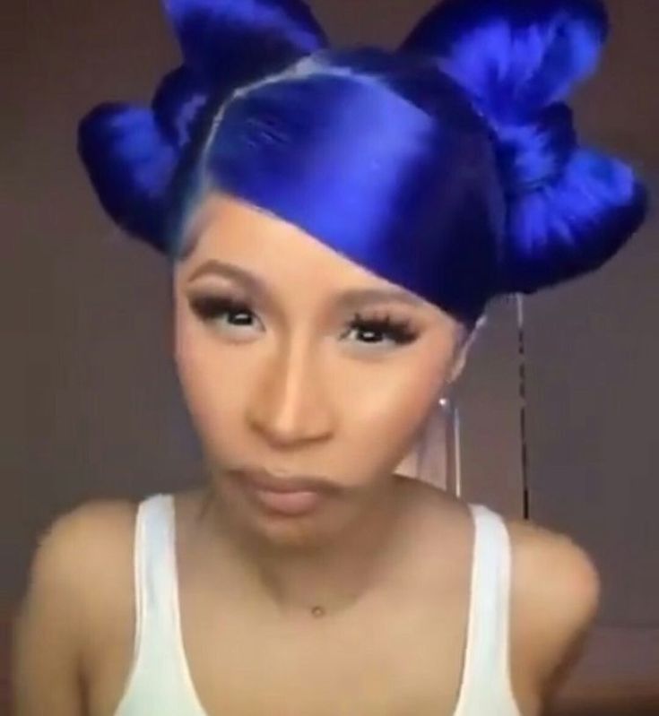 a woman with blue hair and big bows on her head is looking at the camera