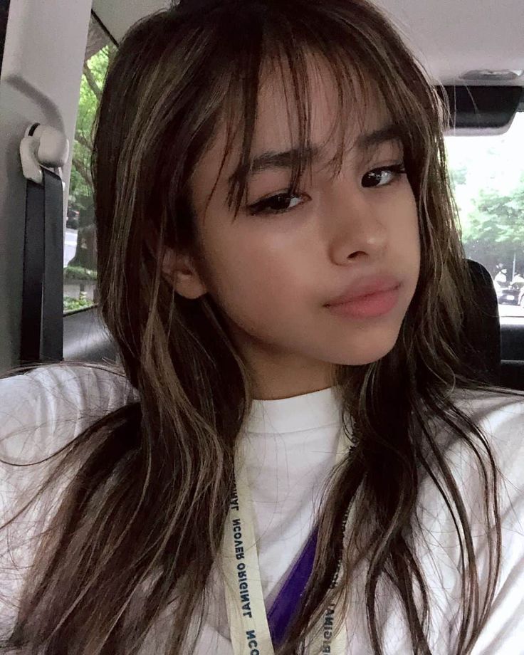 a woman with long hair sitting in the back seat of a car