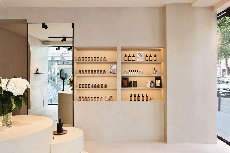 a white counter with bottles and vases on it in front of a store window