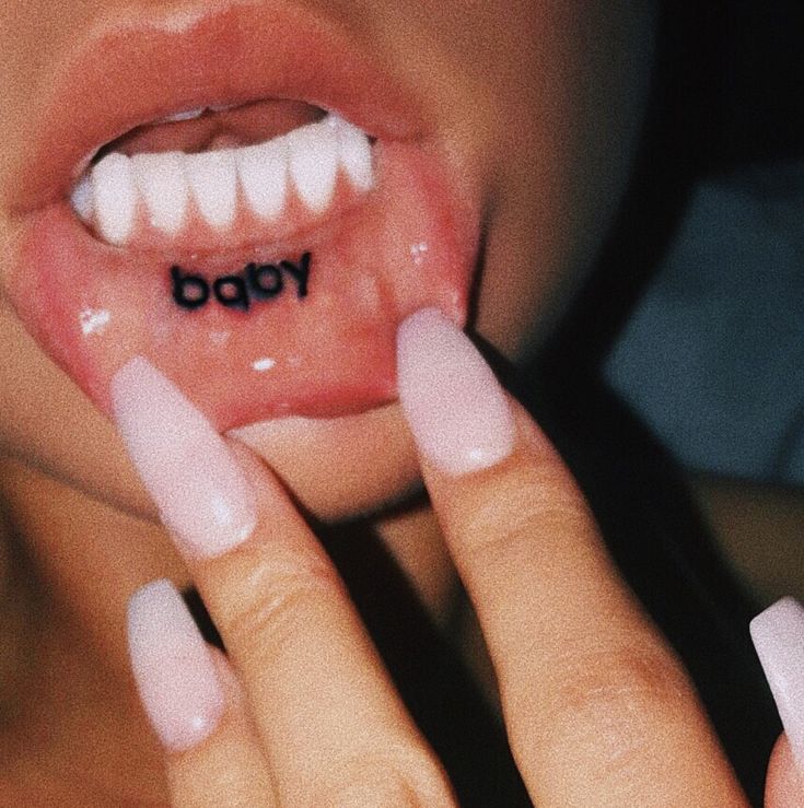 a close up of a person's mouth with the word baby written on it