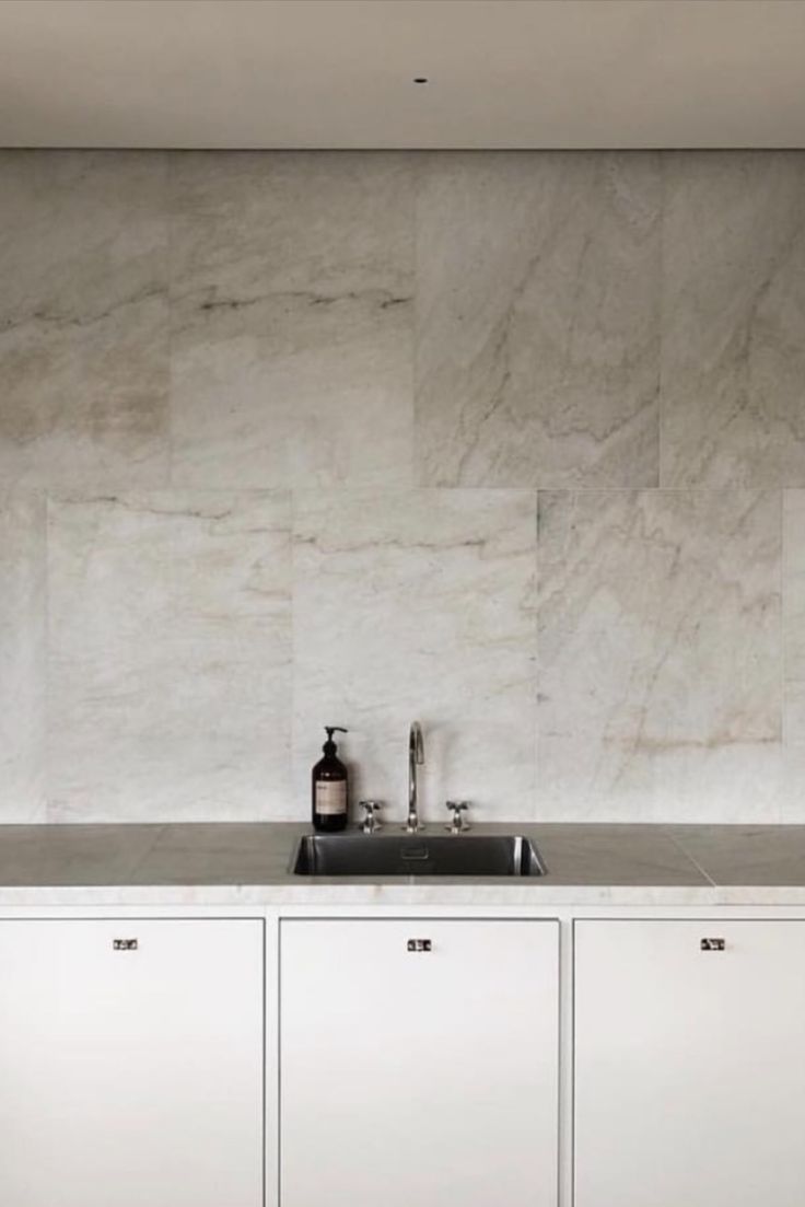 a kitchen with marble walls and white cabinets