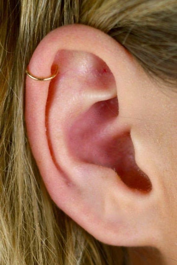 a close up of a person's ear with a gold nose ring