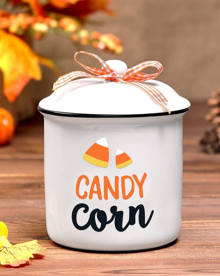 a candy corn canister with a bow on the top and candy corn in the bottom