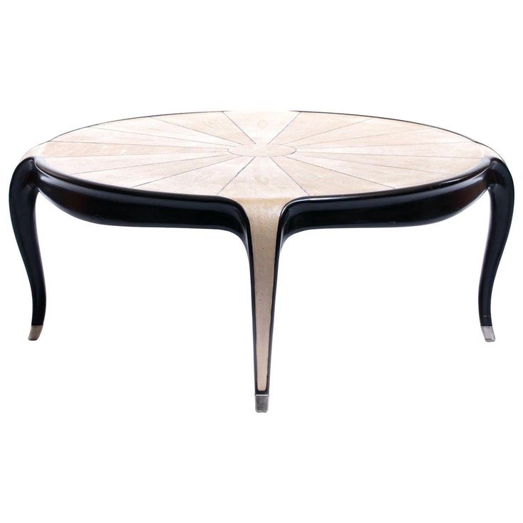 an oval table with black legs and a white flower design on the top, against a white background