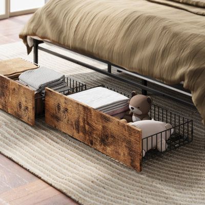 a teddy bear sitting in a cage on the floor next to a bed with pillows