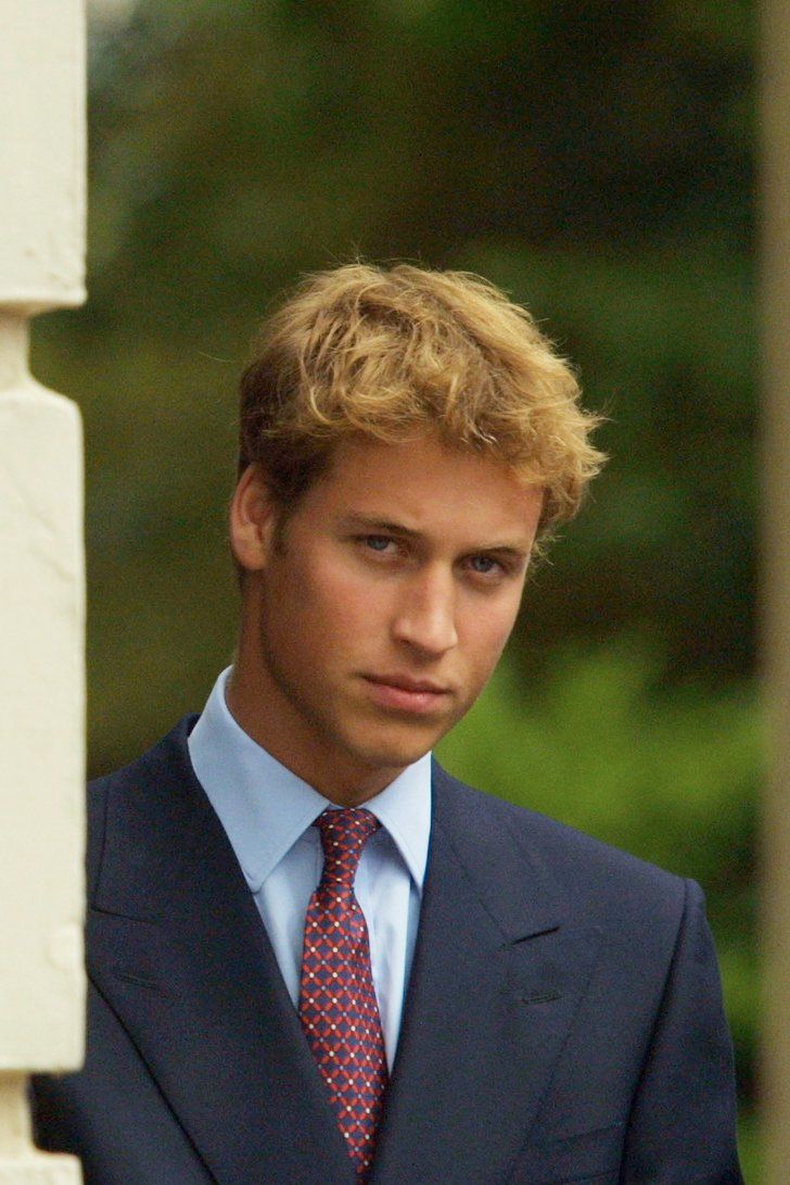 a young man in a suit and tie looking at the camera while standing next to a pillar